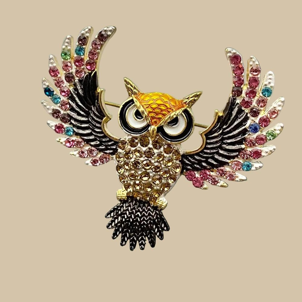 Decorative owl brooch with colorful rhinestones on a light gray background