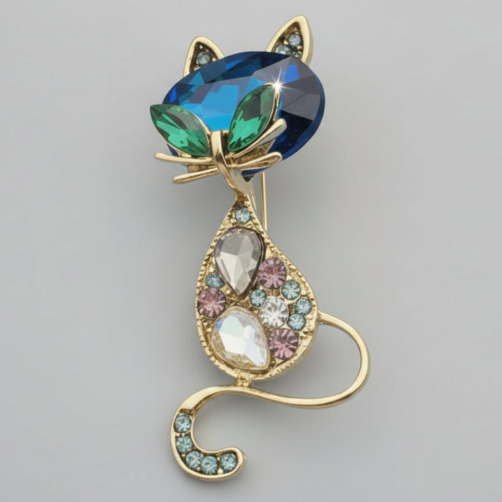 Cat-shaped brooch with facet cut glass and rhinestones on a light gray background