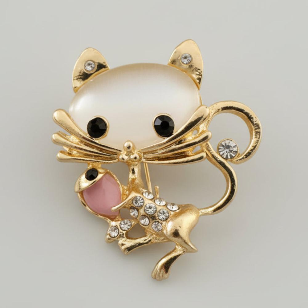 Moonstone mouse brooch with gold accents and rhinestones on a light gray background