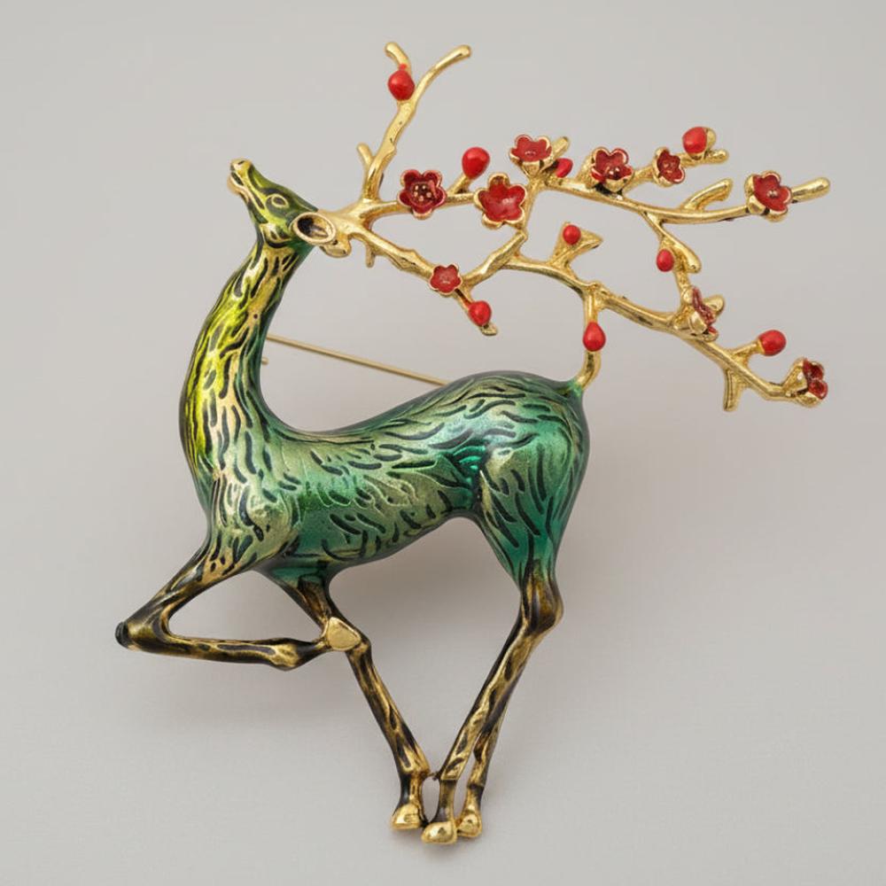 Green sika deer brooch with branch style antlers embellished with red berries on a light gray background