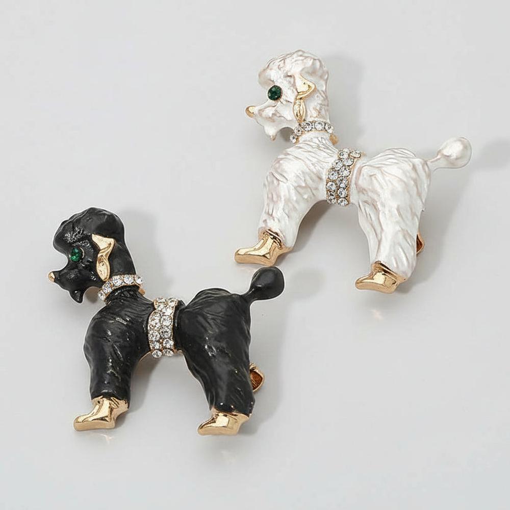 Black and white enamel poodle-shaped brooch with gold accents, on a gray background